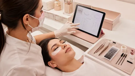 Profesional lash durante un atendimento consultando un tablet